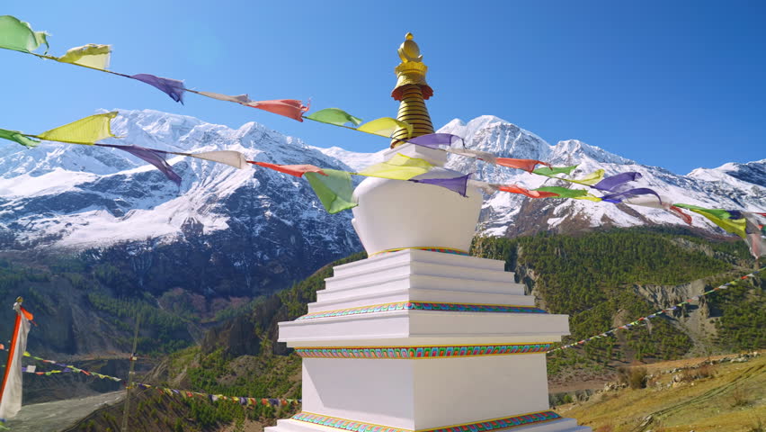 Parallax of Stupa with prayer flags waving in the wind and picturesque sunny Himalaya mountain peak views in the distance, Annapurna, Nepal Royalty-Free Stock Footage #1102145289