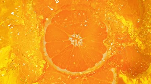 Super Slow Motion Shot of Fresh Orange Slices Falling into Lemonade Whirl at 1000 fps. Video Stok
