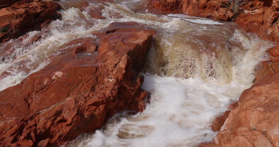 Gunlock reservoir waterfalls red rock Utah slow. State park. Steep red rock landscape flood water from historic snow melt and rain reservoir river. Scenic travel environmental destination.