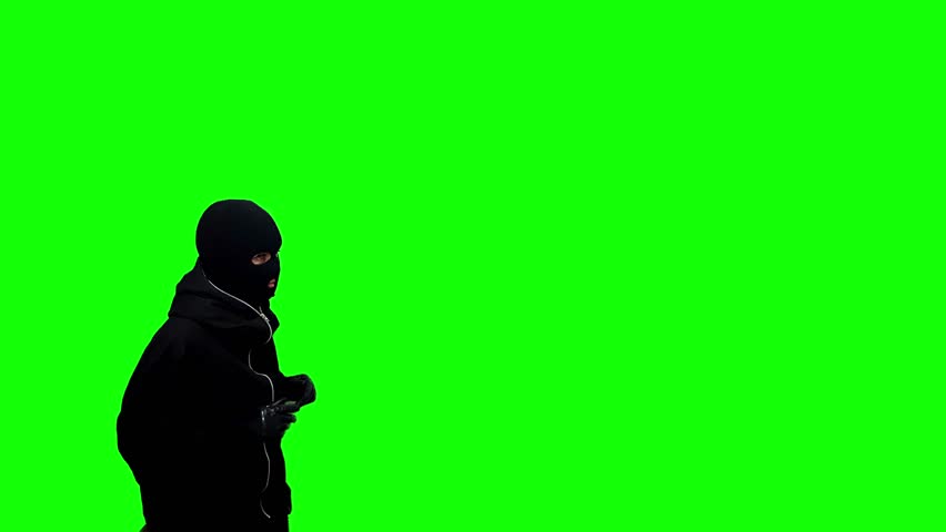Catch concept. thief wearing a black balaclava and gloves raising his hands up isolated on a green background Royalty-Free Stock Footage #1102160111