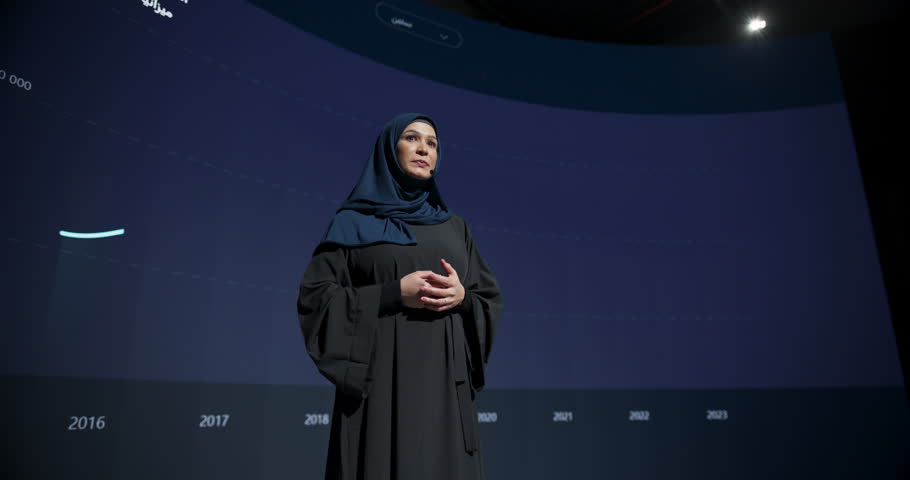 Young Woman Business Executive Introduces New Software Product on Stage at a Conference. Arab Expert Does Motivational Talk. Speaker Having a Lecture about Science, Technology, Development, Leadership Royalty-Free Stock Footage #1102168977