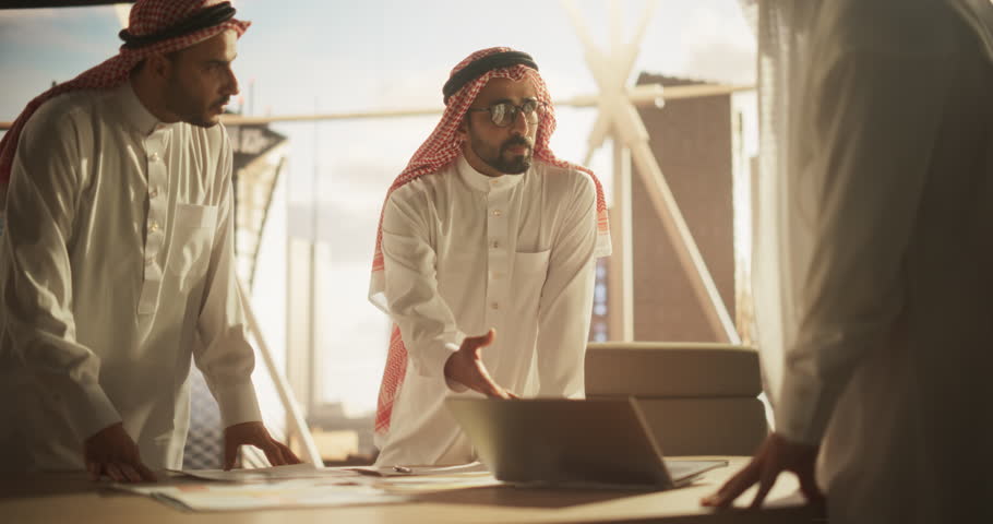 Successful Muslim Businessmen in White Traditional Outfits Having an Office Meeting, Negotiating and Talking About Financial Opportunities. Using Laptop. Saudi, Emirati, Arab Businessman Concept. Royalty-Free Stock Footage #1102169033
