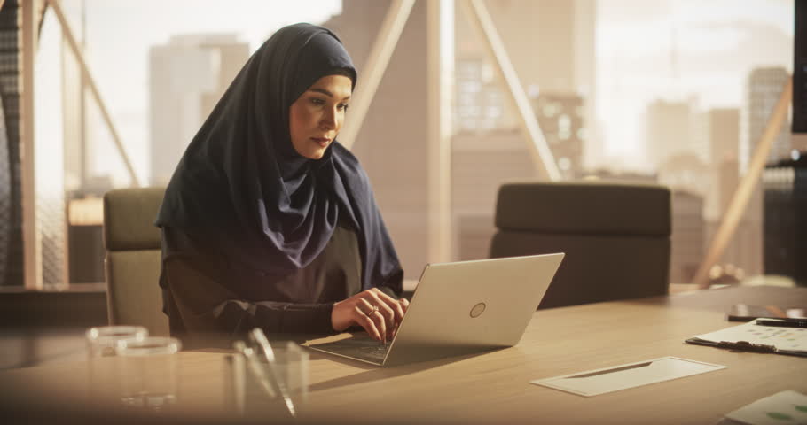 Portrait of a Young Female Business Account Manager Working on a Laptop Computer in a Modern Corporate Office. Businesswoman Dealing with Financial Reports, Preparing a Growth Plan for the Company