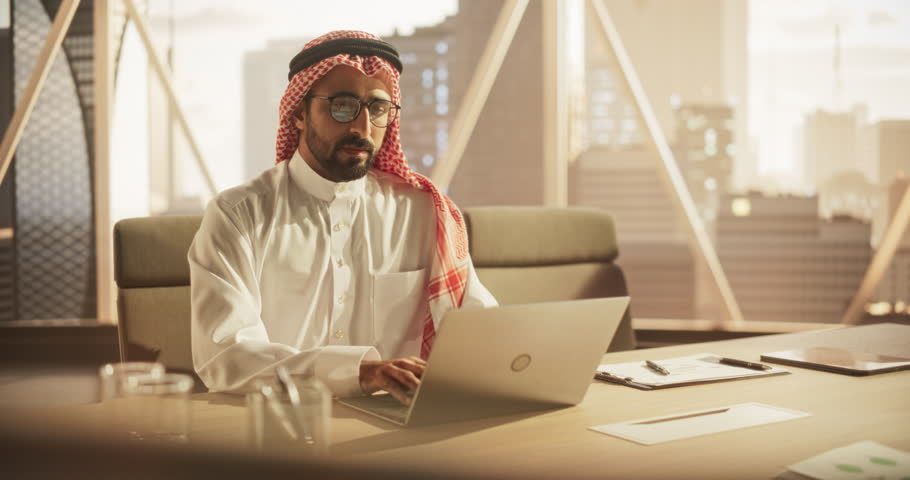 Portrait of a Young Saudi Business Account Manager Working on a Laptop Computer in a Modern Corporate Office. Businessman Dealing with Financial Reports, Preparing a Growth Plan for the Company Royalty-Free Stock Footage #1102169049
