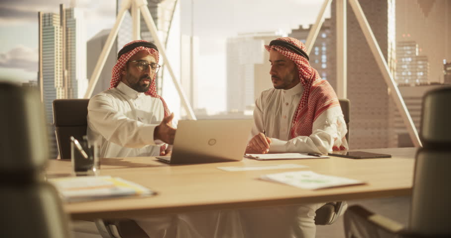 Two Young Middle Eastern Colleagues Working in a Business Software Development Company. Muslim Team Leader Using Laptop Computer, Updating Economic Strategist on a Financial Market News and Trends Royalty-Free Stock Footage #1102169059