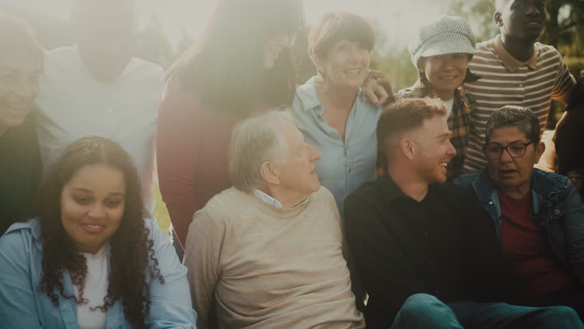 Happy multigenerational people having fun sitting on grass in a public park