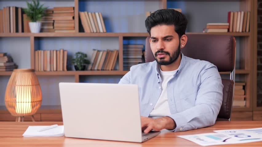 Angry indian man sits in office feels annoyed having problems with laptop. System error, bad e-mail, negative news, data loss, backup battery issues, password wrong, unsaved, lost info need repair. Royalty-Free Stock Footage #1102173745