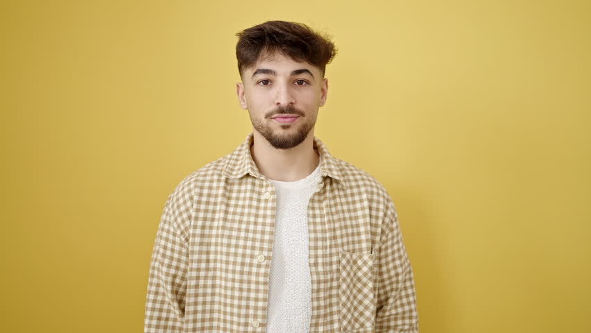 Young arab man smiling confident standing over isolated yellow background