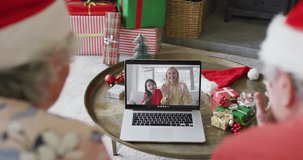 Senior caucasian couple with santa hats using laptop for christmas video call with family on screen. christmas, festivity and communication technology.