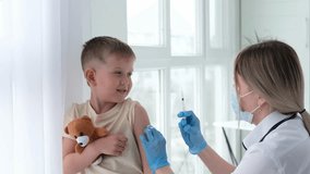 A doctor in a medical mask gives a child an injection in the shoulder. Vaccination, vaccine. The nurse vaccinates the child. Children in the clinic. A little boy gets a flu shot. - Powered by Shutterstock - Get 15% off with code: PIKWIZARD15