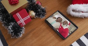 Smiling senior african american couple wearing santa hats on christmas video call on tablet. christmas, festivity and communication technology.
