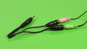 Audio cable splitter, stereo male to two female stereo audio jack 3,5 mm, on green background. Side view. 4K UHD video footage 3840X2160.