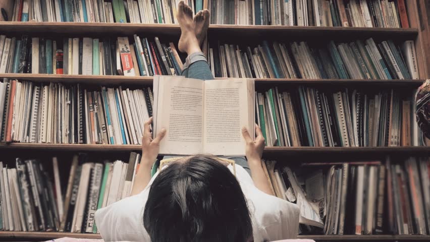 Hispanic woman reading laying on the floor of the library. 4k