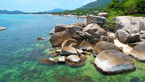 Drone footage captures the rocky Hin Ta Hin Yai outcrop in Koh Samui, resembling male and female genitalia, surrounded by a stunning beach and lush greenery. Thailand. Travel and nature concept

