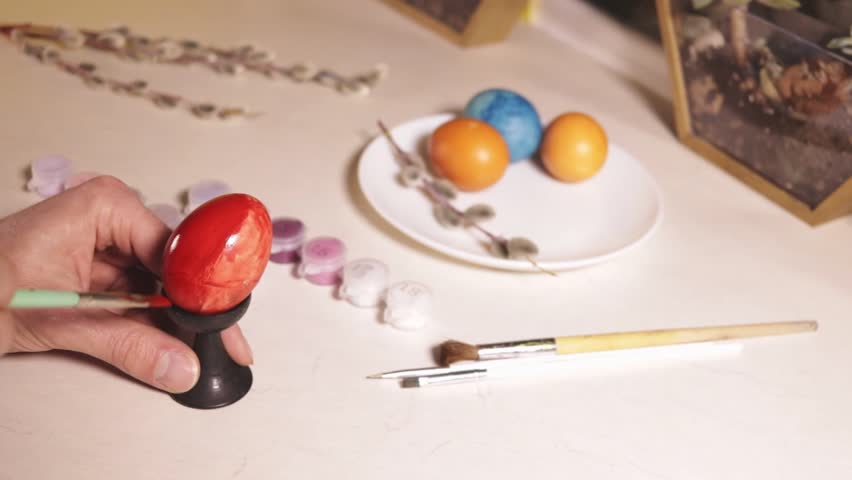 painting an egg red with a brush close-up
