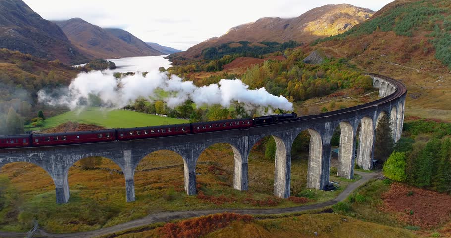 Aerial pan shot of the Jacobite Express crossing the Glenfinnan Viaduct Royalty-Free Stock Footage #1102183685