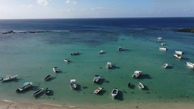 climbing aerial landscape video view of a turquoise blue water bay with small boats anchored close to shore line. video footage from paradise 