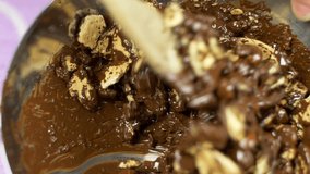 Close up chef amalgam dark chocolate with broken cookies. Traditional Cake preparation. Video