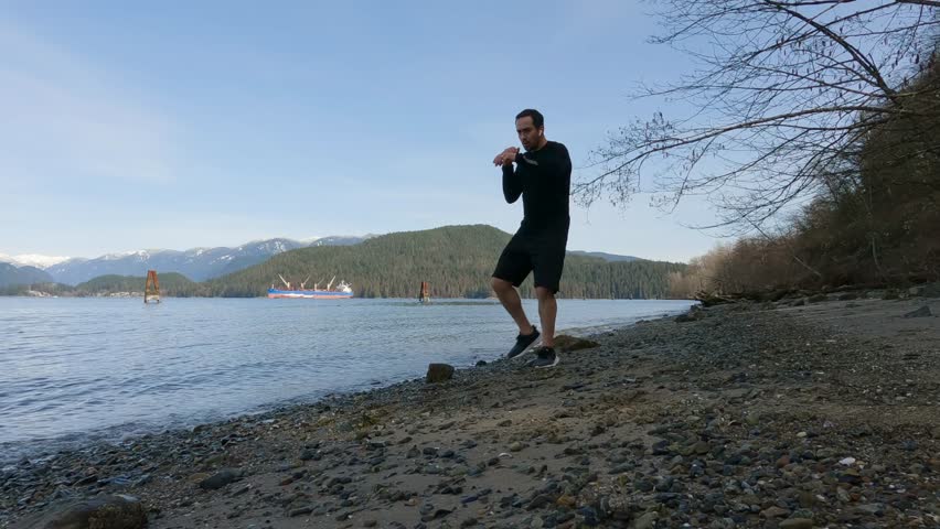 Adult Man Practicing Martial Arts and Shadow Boxing on the beach. Health and Fitness Concept. Port Moody, Vancouver, British Columbia, Canada.