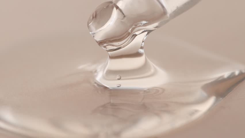 Cosmetic gel, hyaluronic acid in a glass pipette on a beige background, macro. Beauty concept.