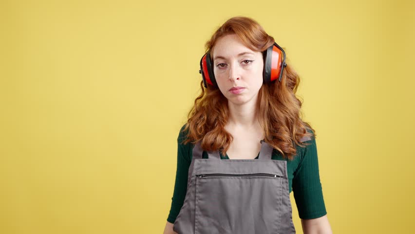 Serious redheaded female worker standing with arms crossed