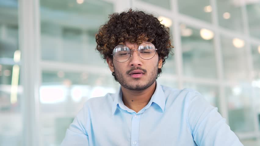 Webcam view. Close up of amazed happy man looking surprised at camera or laptop screen while sitting in office. Excited man shots glasses. He read shocking news or saw interesting content. Wow effect Royalty-Free Stock Footage #1102192825
