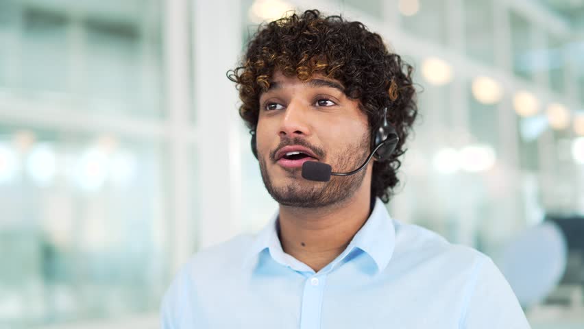 Close up. A corporate operator who works in the support service speaks on a video call. A call center agent in a wireless headset helps a customer with a complaint in a office by answering questions Royalty-Free Stock Footage #1102192855