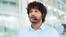 Close up. A corporate operator who works in the support service speaks on a video call. A call center agent in a wireless headset helps a customer with a complaint in a office by answering questions