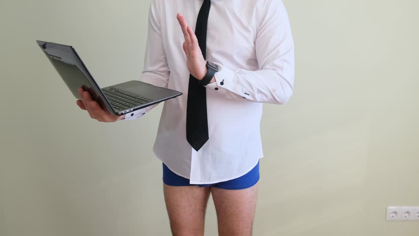 A man in underwear and a business shirt is holding a laptop while standing on a white background