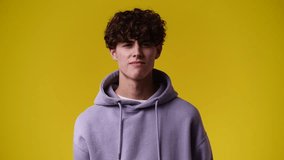 4k video of smiling man showing thumb down on yellow background.