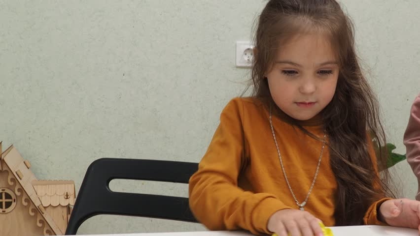 Young Smiling girl Cleaning House. Closeup of Happy Beautiful Girl wearing Cleaning Desk by spraying Cleaning Products and wiping with Sponge. daughter helps mom Woman Cleaning Apartment