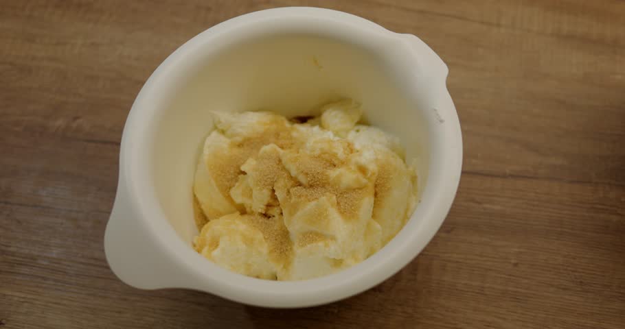Female hand hold table spoon pour flour to white bowl for cream recipe. Confectioner adds powder to mixed ingredients to prepare tasty sweet pastry cream. High quality 4k footage