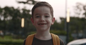 Portrait Handsome of a happy school boy, a smiling school boy, a little boy with a backpack, standing alone on a sunny street outdoors, a pretty face primary first grade student 4 K.