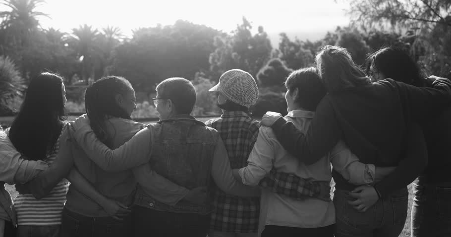 Crowd of multigenerational women hugging each other outdoor - Multiracial female friends with different ages having fun together at city park 