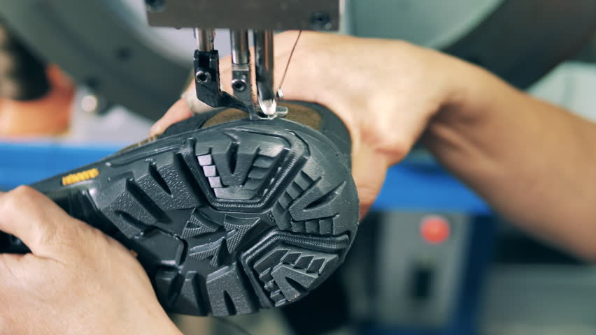 Shoemaking industry concept. Factory worker attaching sole to a shoe using a machine