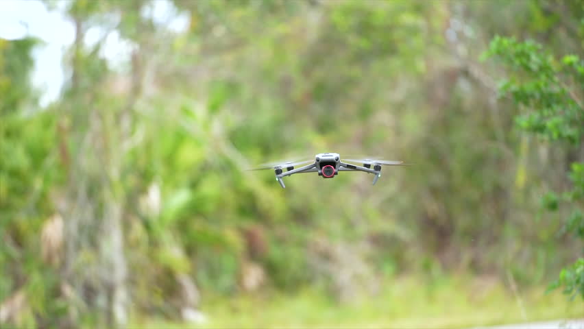 Drone aircraft with blurred fast rotating propellers and video camera flying in air