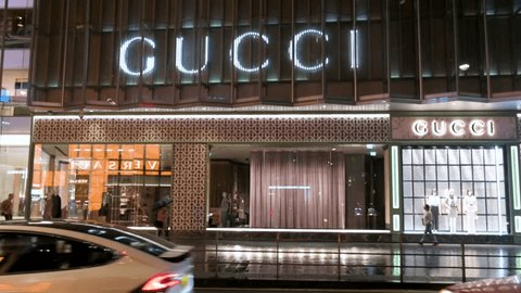Hong Kong , China - 03 31 2023: Pedestrians walk past the Italian luxury fashion brand Gucci logo and store during nighttime and rainy weather. Adlı Haber Amaçlı Stok Video