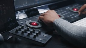 Hands close up of African American film editor working by color grading control surface in studio with modern design. Colorist does colour correction for movie post production. Professional equipment.
