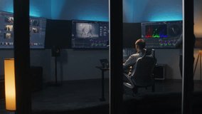 Multi ethnic colorist and film maker edit video and make color grading in program. Process of colour correction for movie post production in modern studio. Multiple monitors with action film footage.