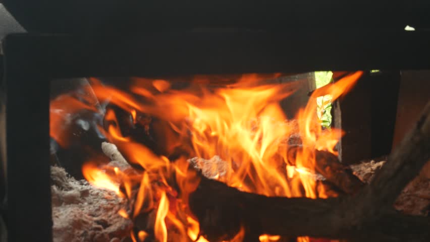 Pan on the stove over a natural fire for cooking, Cooked meal in nature, Detail of orange fire, Close view at hot fireplace full of wood and fire.