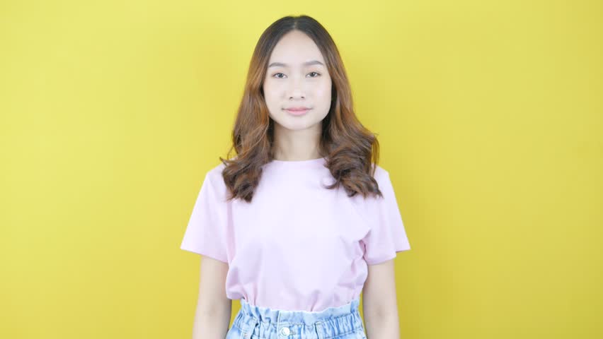 Woman showing Y2k pose. Asian retro fashion on yellow background.