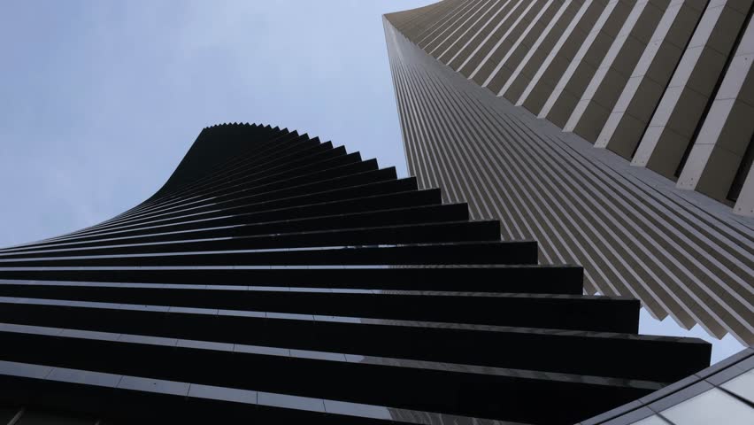 Bottom view. Two beautiful modern office skyscrapers against the sky. Building exterior, business, construction industry. Image rotation.