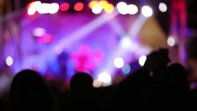 Silhouettes of concert crowd with stage lights, out of focus blurred video.