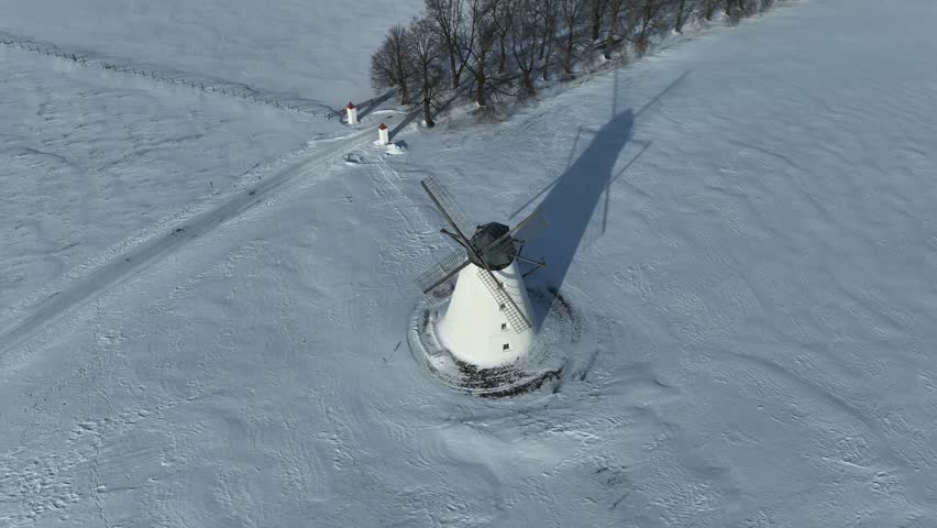 Rotating aerial view of Vihula windmill in winter with white snow covering the ground. Lahemaa, Estonia.