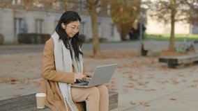 Online Meeting, Conference. Happy Asian Student Sitting on the Bench, Using Laptop, Having Distant Lecture, Waving at the Camera, Using Earphones. Lady Studying Online. People and Technology Concept