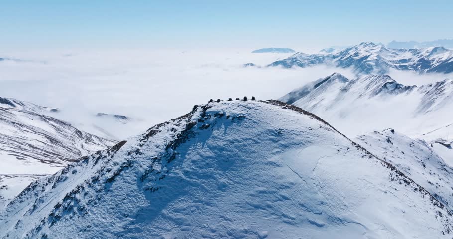Mountains and hills covered by snow as one falls another rises from aerial view in morning. Aerial picture of a heaven of serenity in countryside of China in winter.