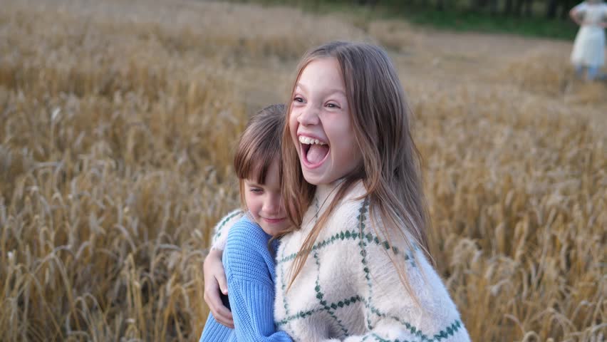 Two cute and friendly sisters have fun on a summer day in nature during a walk. People and nature.