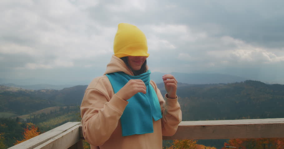 young woman traveler in the mountains puts on warm clothes. autumn cold weather. Generation Z travel