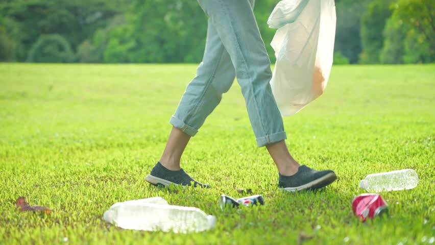 Asian volunteer woman walking collecting in bag a trashes on green grass area inside the public park during the sunny day. Plastic pollution. Environmental problem and care. Save the planet. Royalty-Free Stock Footage #1102223129