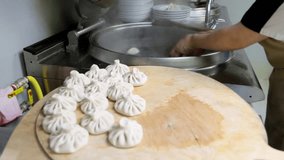 Cook quickly puts khinkali into boiling water at commercial kitchen. Georgian traditional cuisine 4k video.